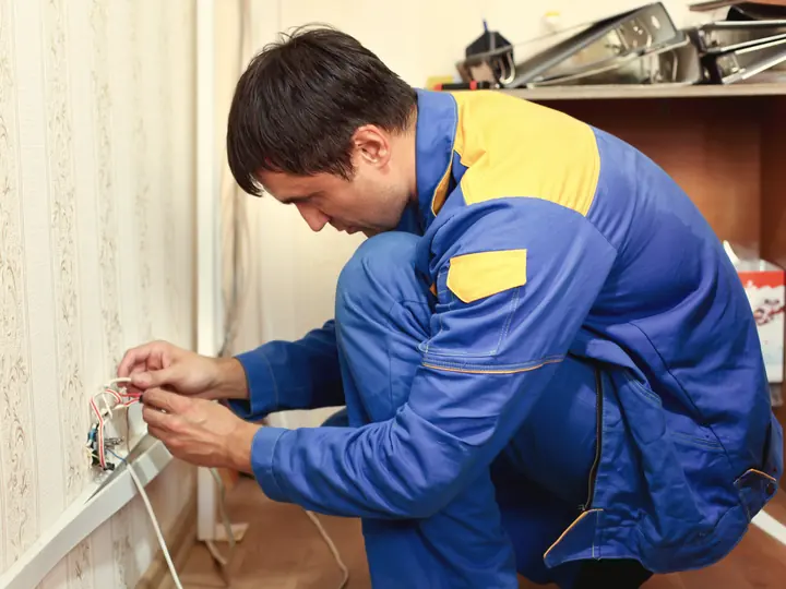Électricien installant une prise murale dans une résidence